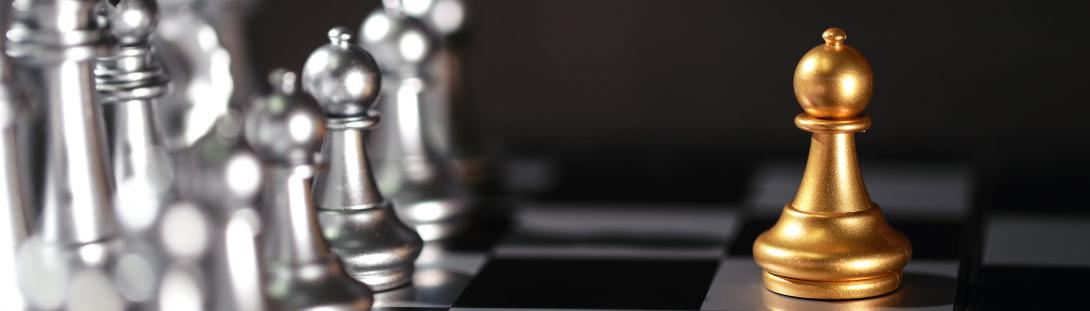 A single chess pawn standing off against a chess board
