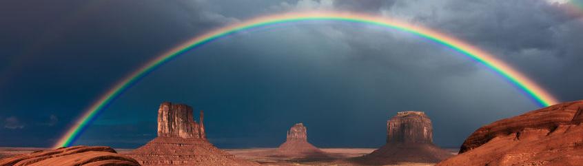 red mountains with dark skies and rainbows