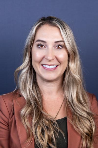 photograph of Nicole Sornsin, she has long blond hair, brown eyes, and she is wering a black blouce with burgendy blazer