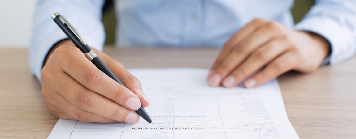 Person filling out a job application on paper with a pen