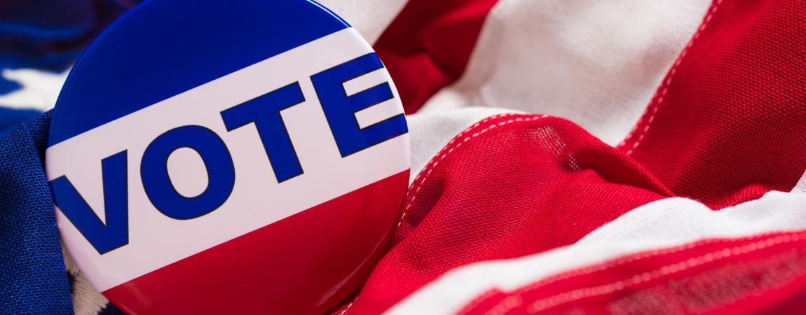 An American flag with a buttom that says VOTE