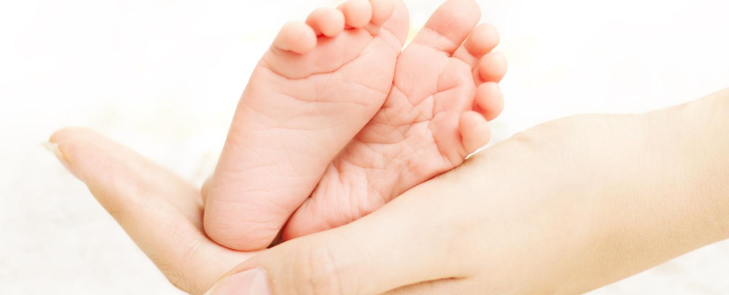 adult hands holding baby feet
